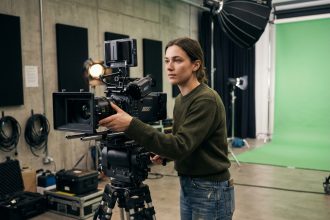 Étudiante en réalisation cinématographique ajustant une caméra professionnelle dans un studio de formation